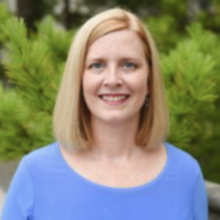 A headshot of Dr. Abbey Dvorak with a pine tree in the background
